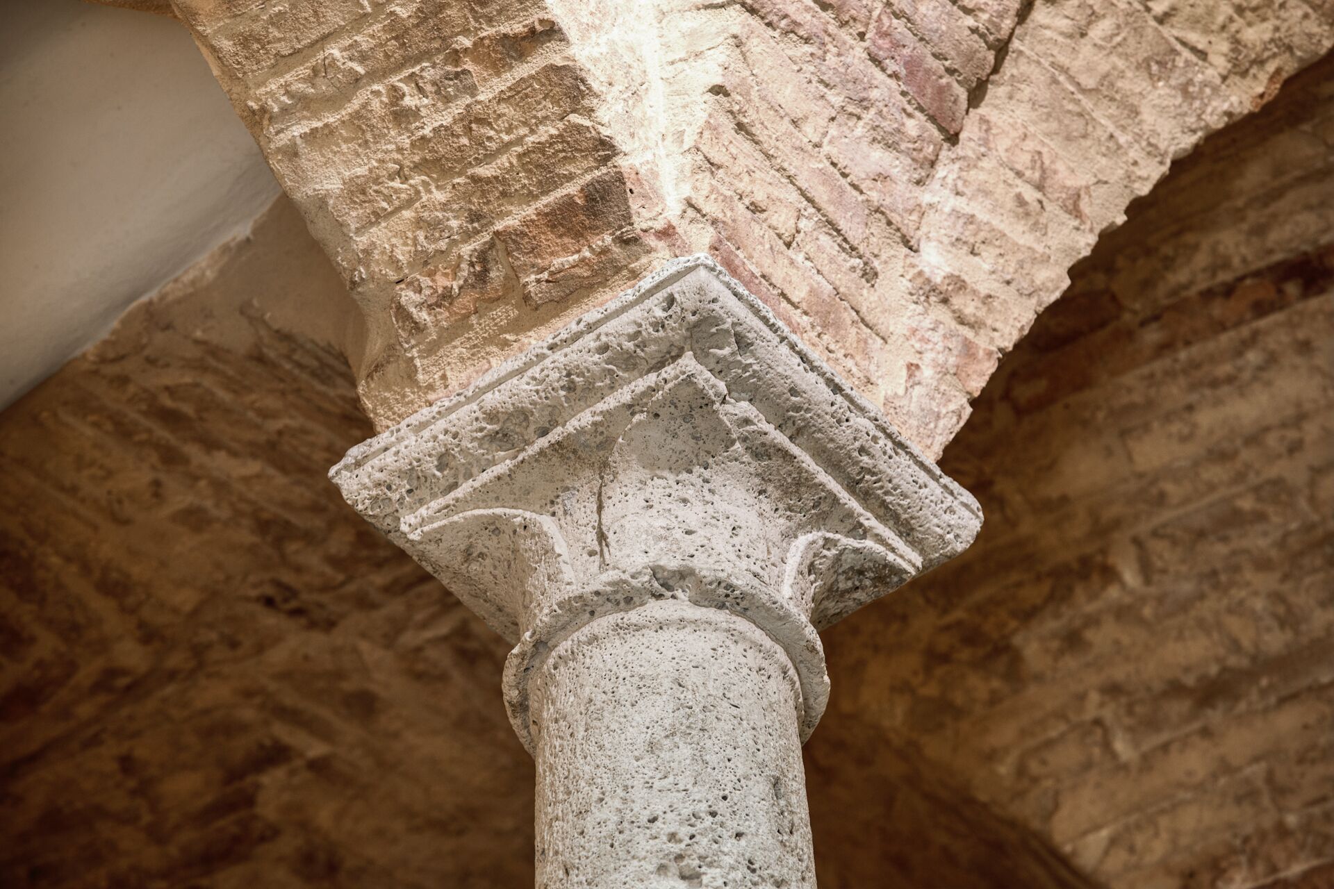 A close-up of a stone column with a capital at the top, part of a larger architectural structure.