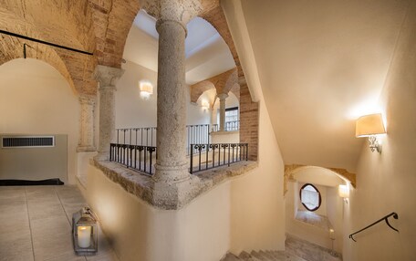 A spacious interior with a high ceiling, stone columns, and a staircase leading to an upper level.
