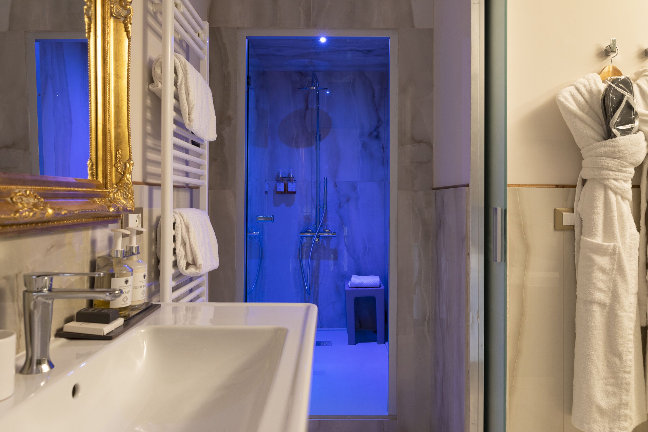 A modern bathroom with a large mirror, a sink, and a shower area.