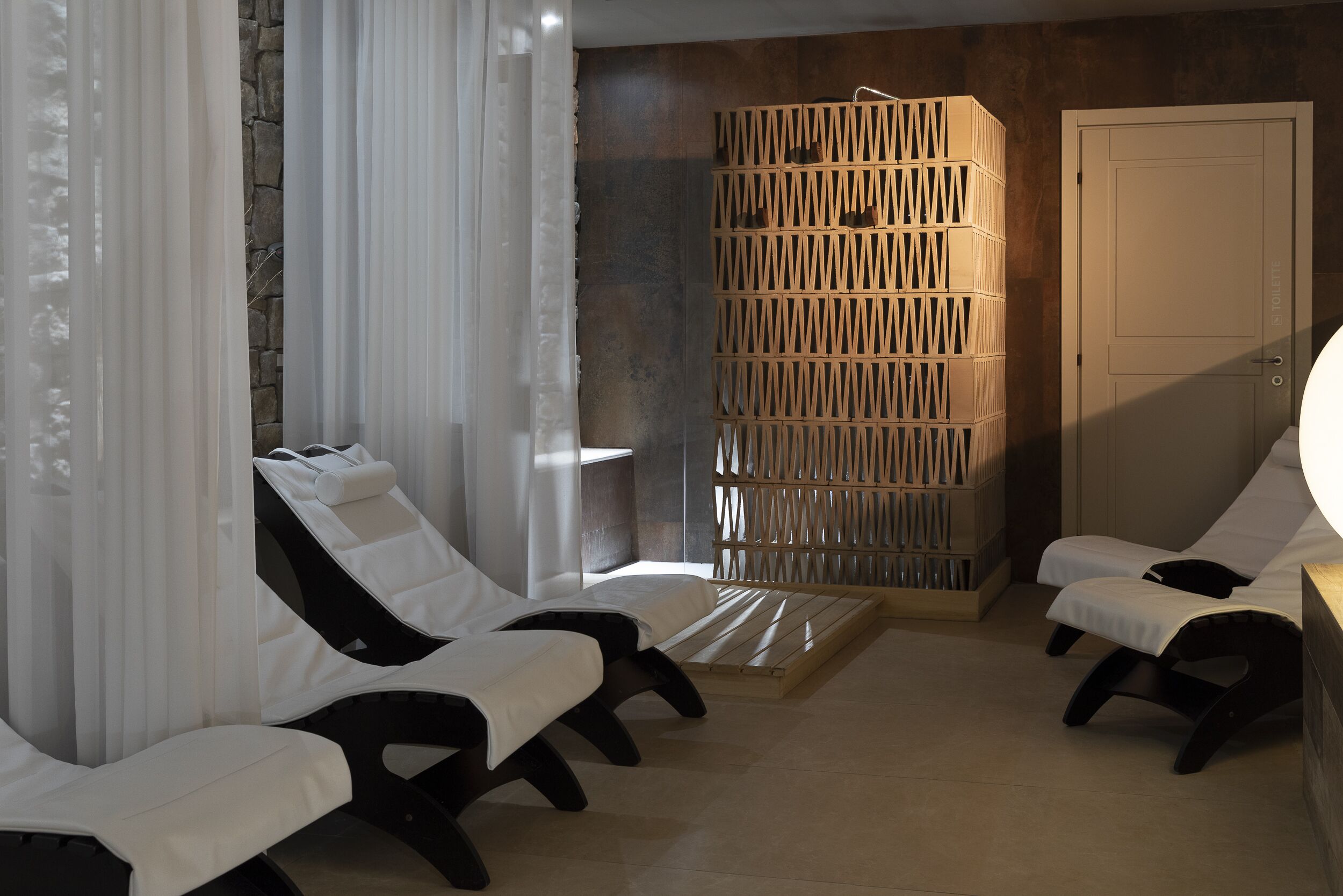 Un cuarto de spa con dos sillones reclinables, un separador de madera y una puerta.