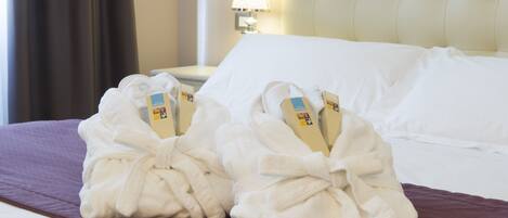 A hotel room with a neatly made bed, a bedside lamp, and a window with curtains.