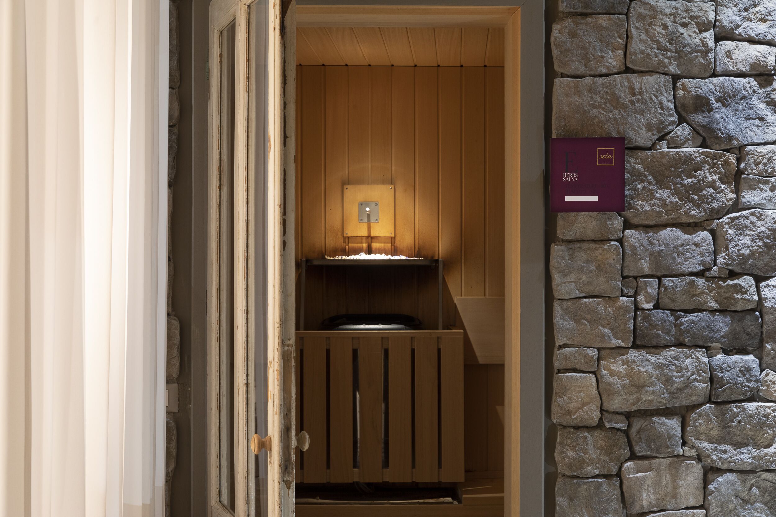 Una sauna in legno con una parete in pietra e un'indicazione che si tratta di una sauna.