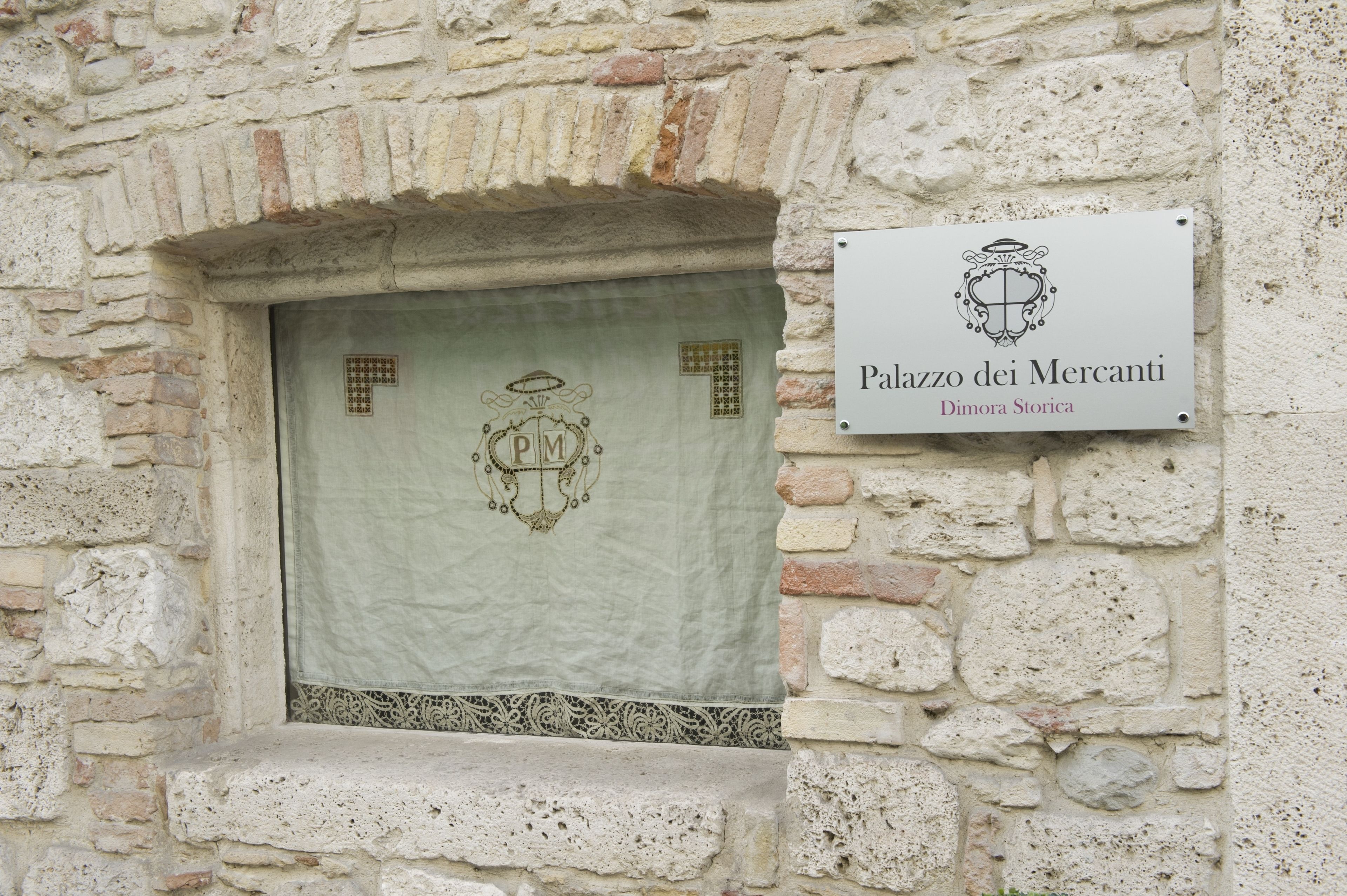 Un muro de piedra con una placa que dice 'Palazzo dei Mercanti Dimora Storica'.