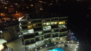 Un hôtel à plusieurs étages doté d’une piscine et d’un espace extérieur aménagé pour s’asseoir.