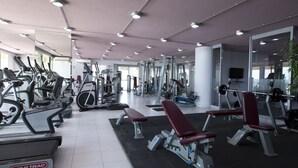 Une salle de sport équipée de divers appareils d’exercice, notamment des tapis de course, des vélos d’appartement et des appareils de musculation.