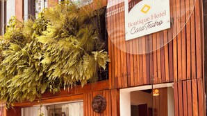 Entrada de un hotel boutique con paneles de madera, una decoración con cabeza de león y un cartel con el nombre.