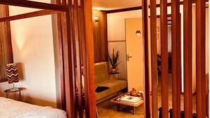 Un dormitorio con cama, sofá, una mesita de centro y un separador de madera.