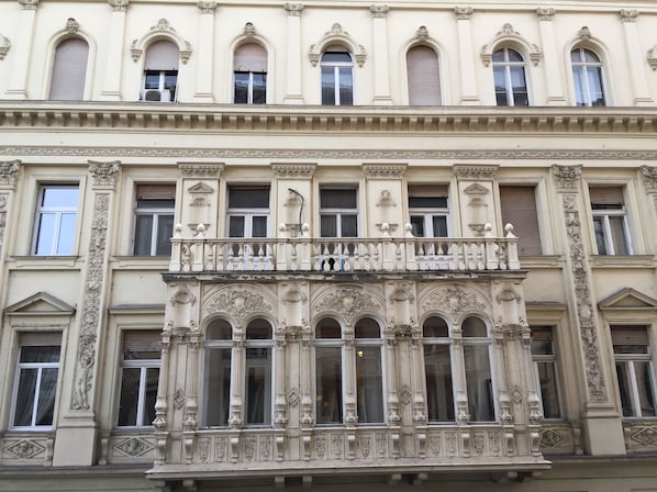 A building with ornate architectural details, including a balcony with decorative balustrades and multiple arched windows.