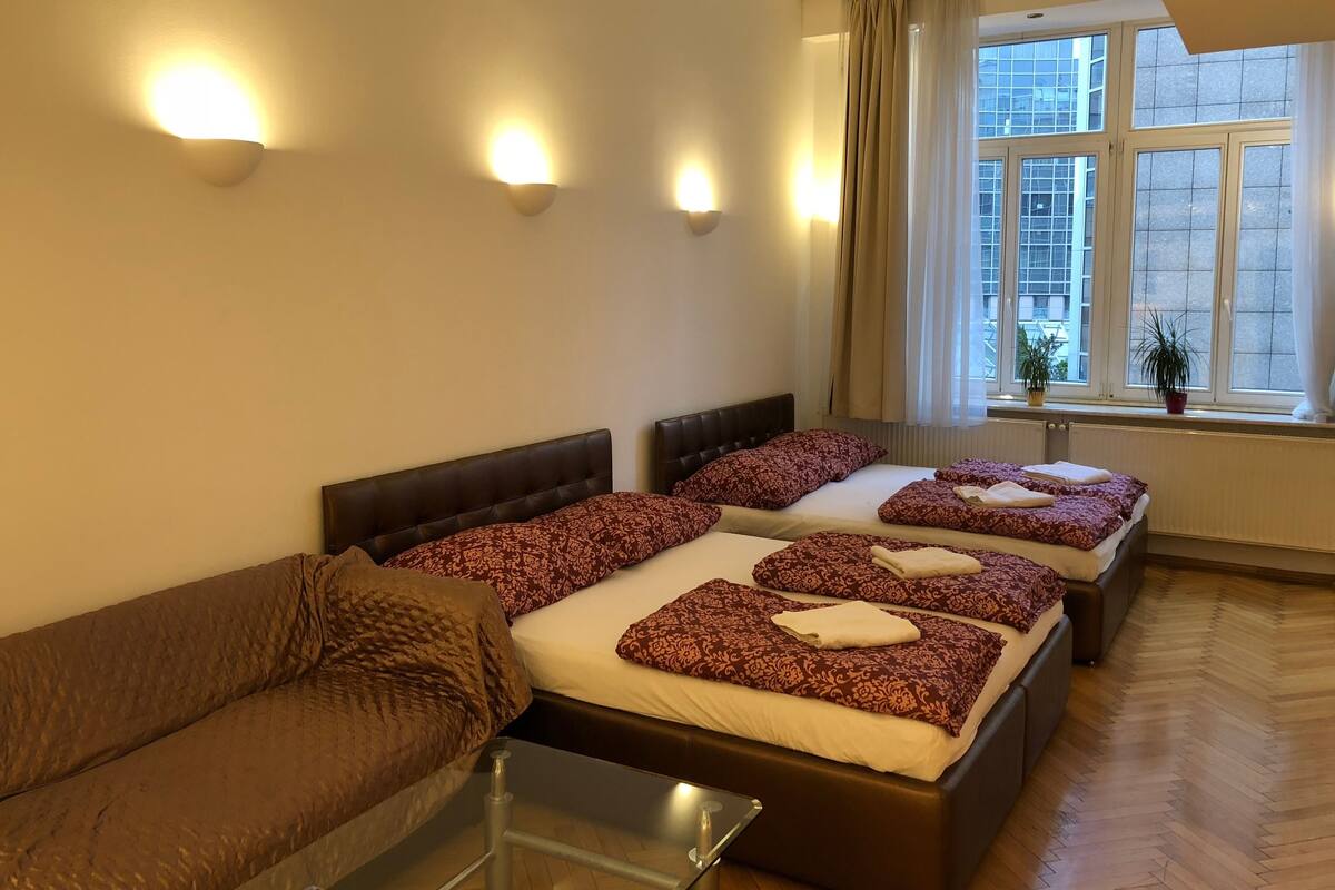 Habitación de hotel con dos camas, un sofá y una ventana con cortinas.