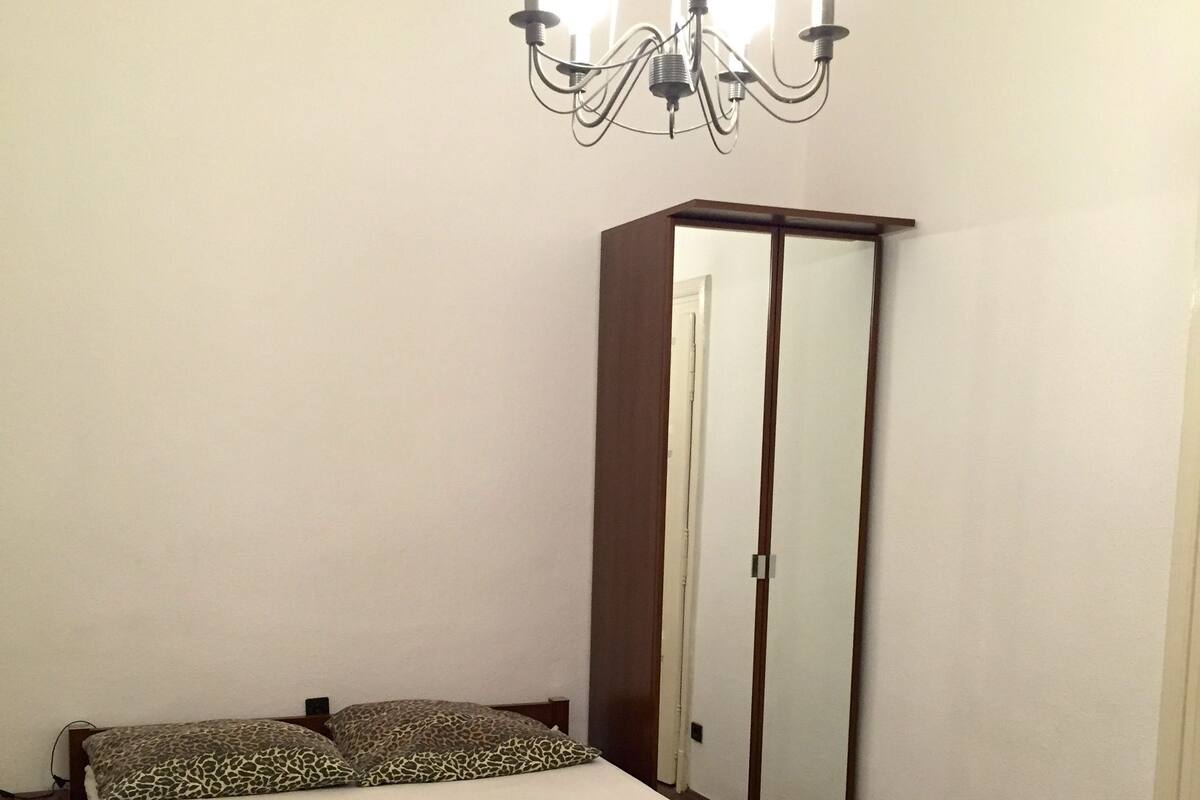 Un dormitorio con una cama de madera, un mueble espejo y una araña.
