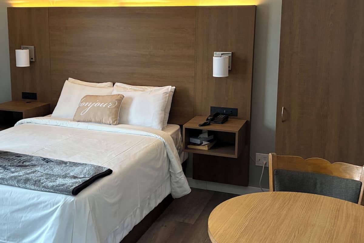 Une chambre d’hôtel avec un lit, des tables de chevet, un bureau et une chaise.
