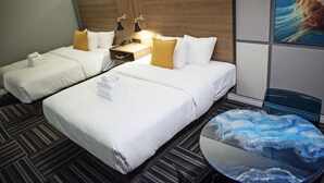 Une chambre d’hôtel avec deux lits, une table ronde au motif évoquant le marbre et un tableau représentant une méduse accroché au mur.