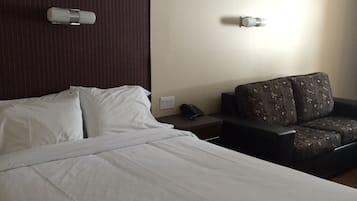 A hotel room with a large bed, a sofa, and two wall-mounted light fixtures.