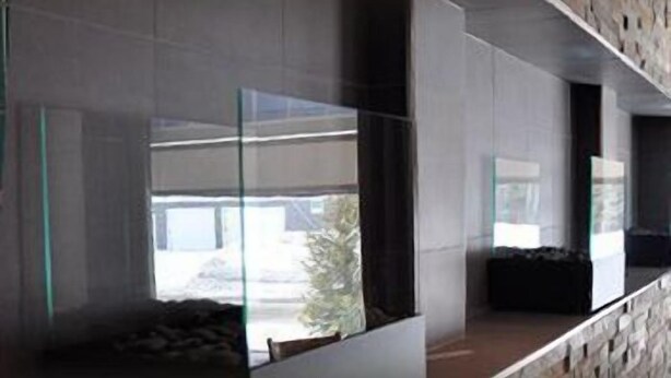 Un intérieur moderne avec un mur en pierre, une cloison en verre et une vue sur l’extérieur.