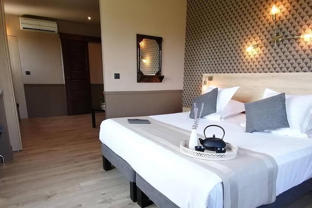 A neatly made bed with a tray, a bedside table, a wall-mounted light fixture, and a door in the background.