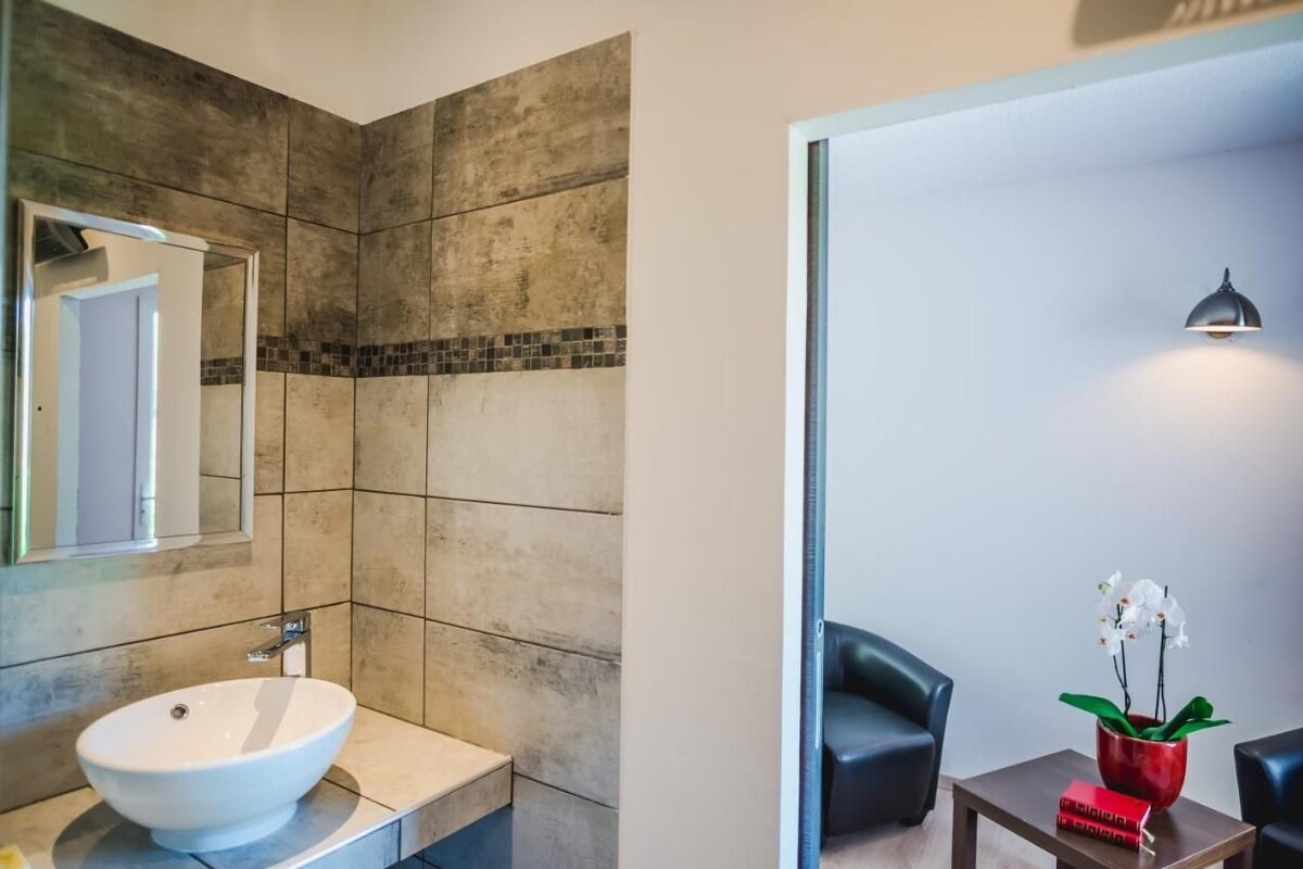 A modern bathroom with a large mirror, a white sink, and a shower area.