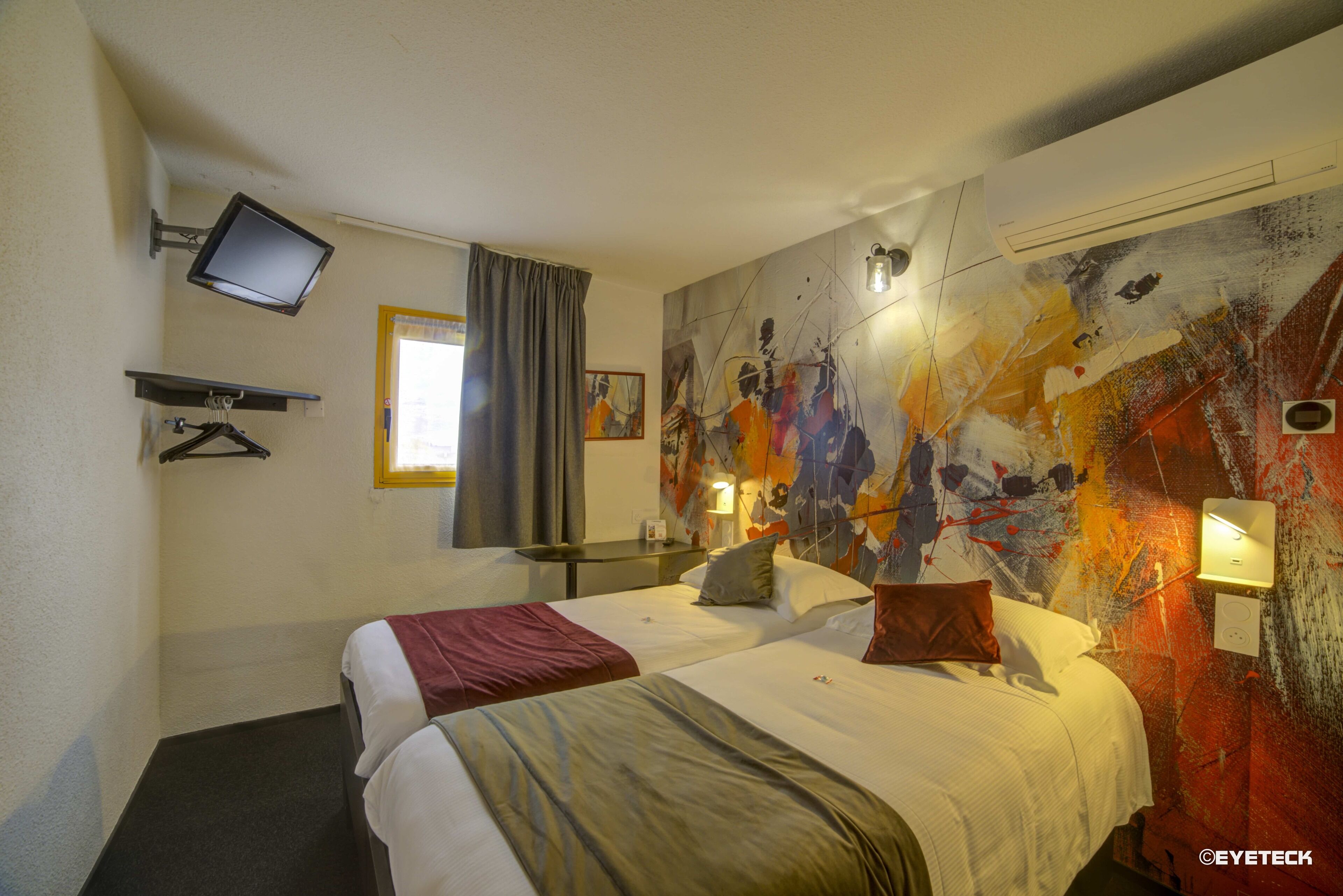 A hotel room with two beds, a flat-screen TV, a painting on the wall, and a window with curtains.