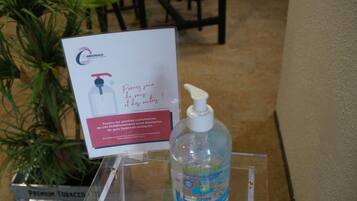 Un dispensador de gel hidroalcohólico sobre un soporte transparente con un letrero sobre higiene en espacios públicos.