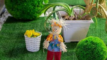 A miniature garden with a doll, potted plants, and a small white basket.