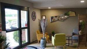 A lobby with a large window, a dartboard, a mirror, and a plant. - The Originals Access Bourges Nord (Saint-Doulchard)