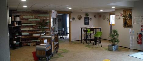 A hotel lobby with a wooden wall, a reception desk, and a seating area with chairs.