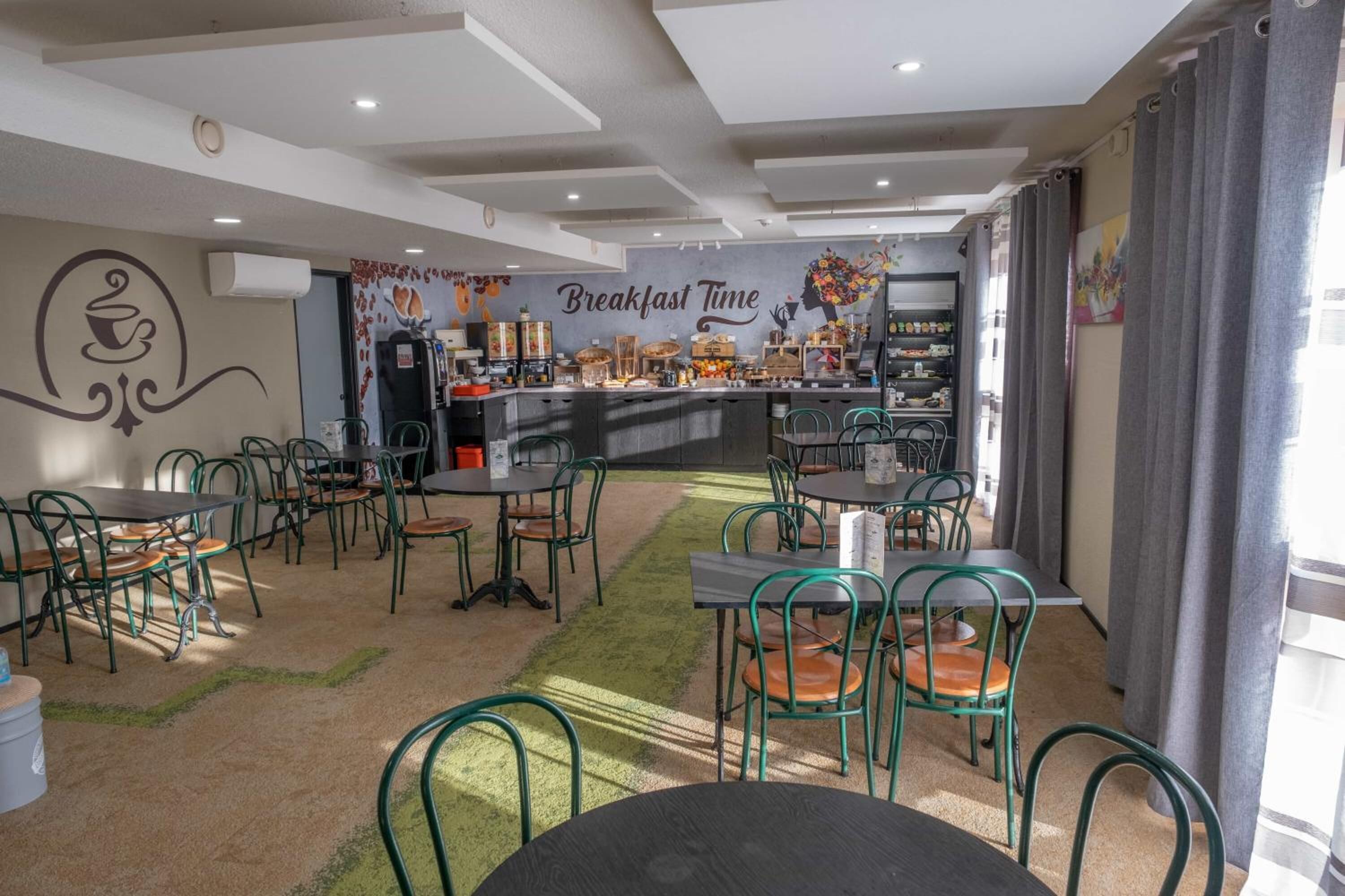 Un'area colazione con tavoli e sedie, una macchina da caffè e un muro decorato con un murale raffigurante 'Breakfast Time'.
