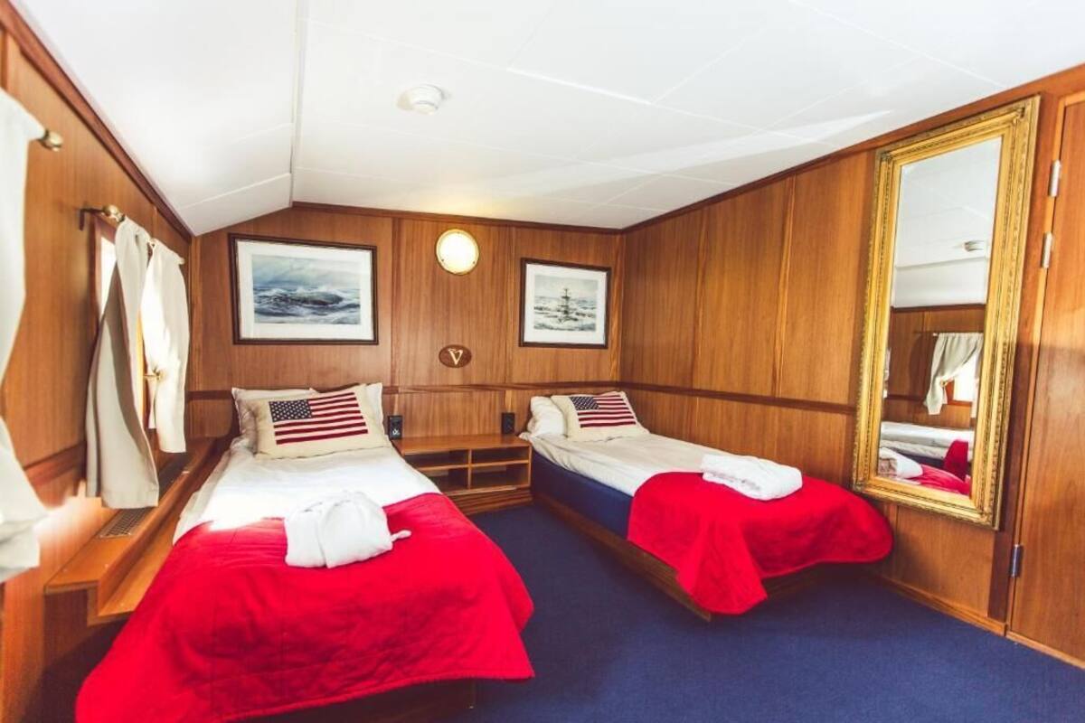 Een blokhut met twee bedden, houten lambrisering, een grote spiegel en ingekaderde foto's aan de muur.
