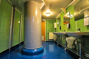 A restroom with green walls, two sinks, a large pillar, and a blue floor.
