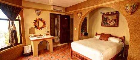 A bedroom with a bed, a vanity with a mirror, a ceiling fan, and a window with curtains.