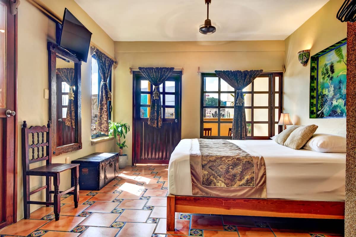 A bedroom with a bed, a desk, a chair, a window, and a door.