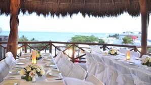 Un área de comedor al aire libre con mesas preparadas para una comida, con vista al mar.