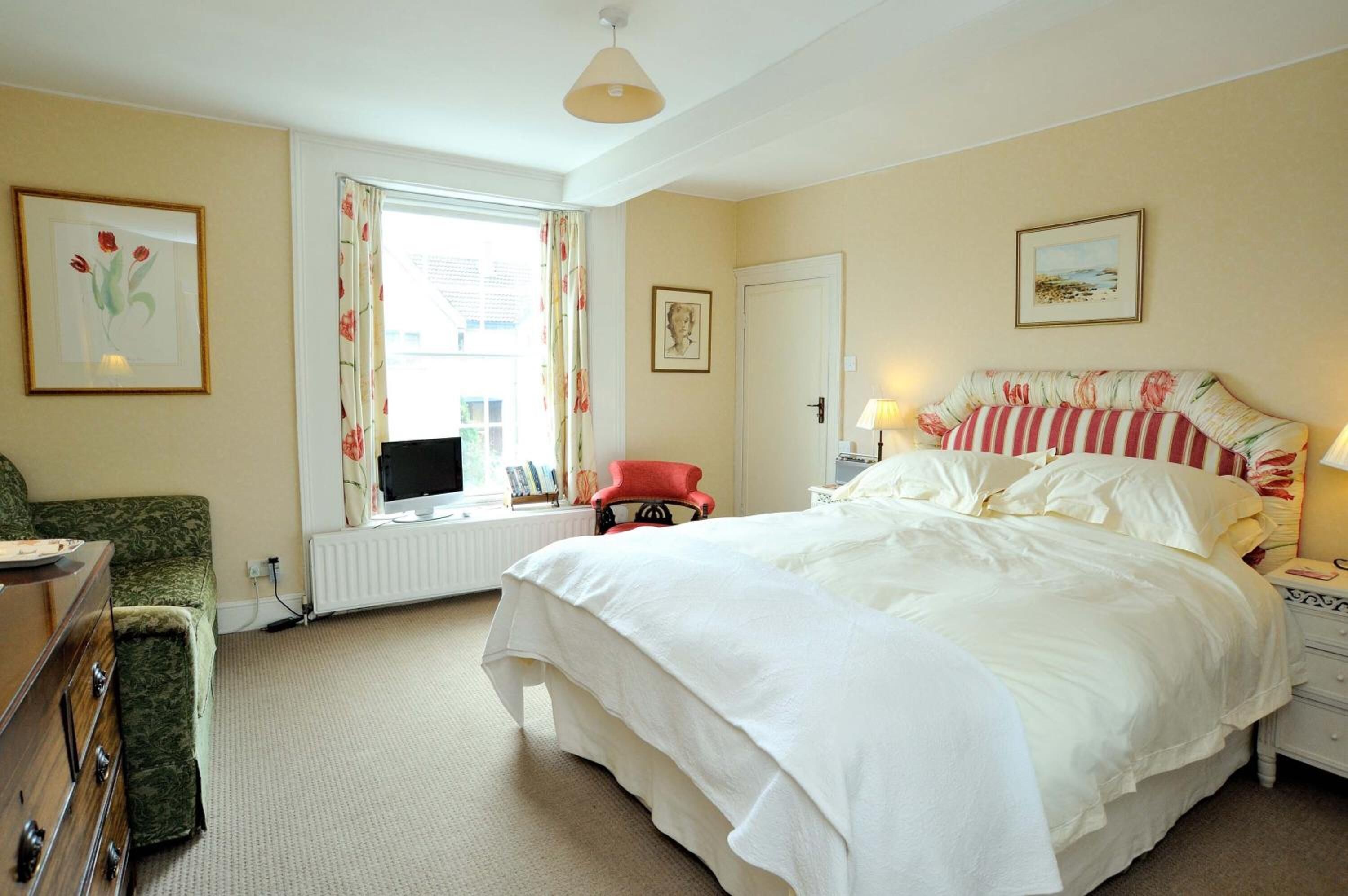 A bedroom with a large bed, a desk, a chair, and a radiator.