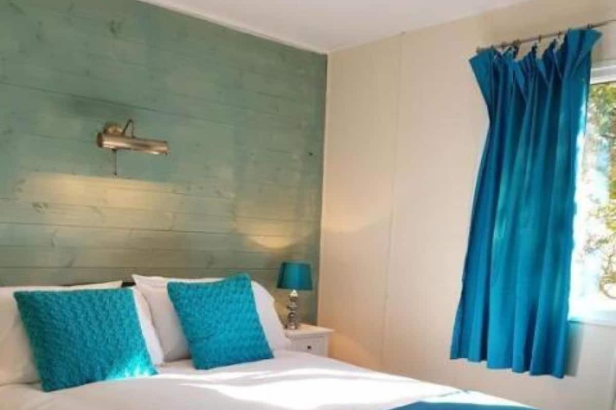 A bedroom with a bed, a nightstand, a lamp, and a window with curtains.