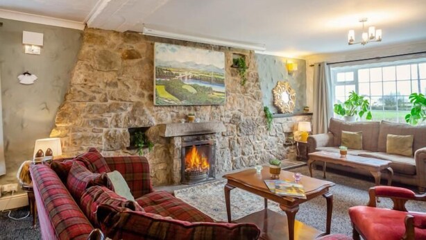 A cozy living room with a stone fireplace, a sofa, a coffee table, and a painting of a landscape.