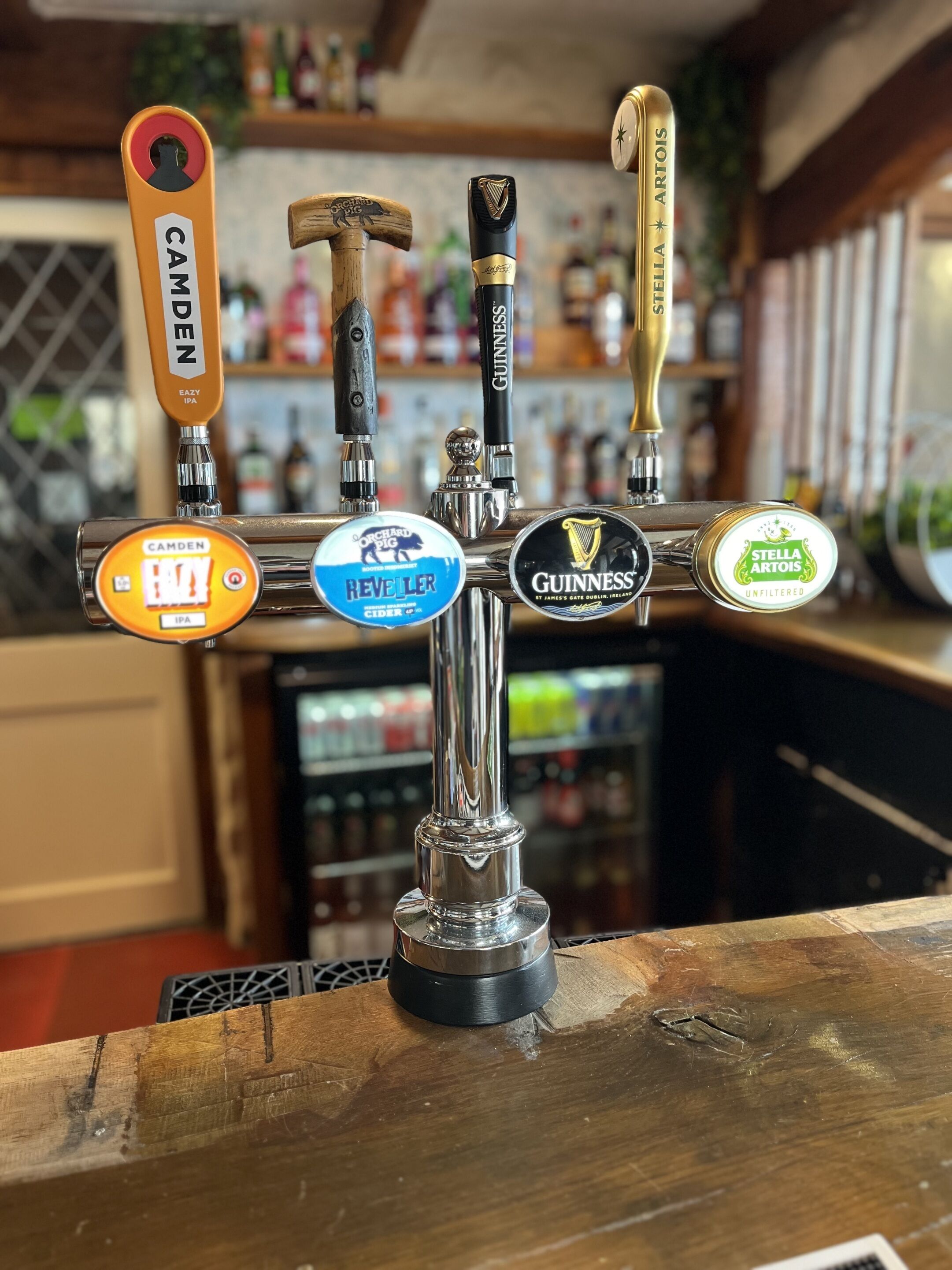 Ett tappsystem för en bar med flera ölfat, där varje fat är märkt med namnen CAMDEN, ORCHARD PIG, REVELER, GUINNESS och STELLA ARTOIS.