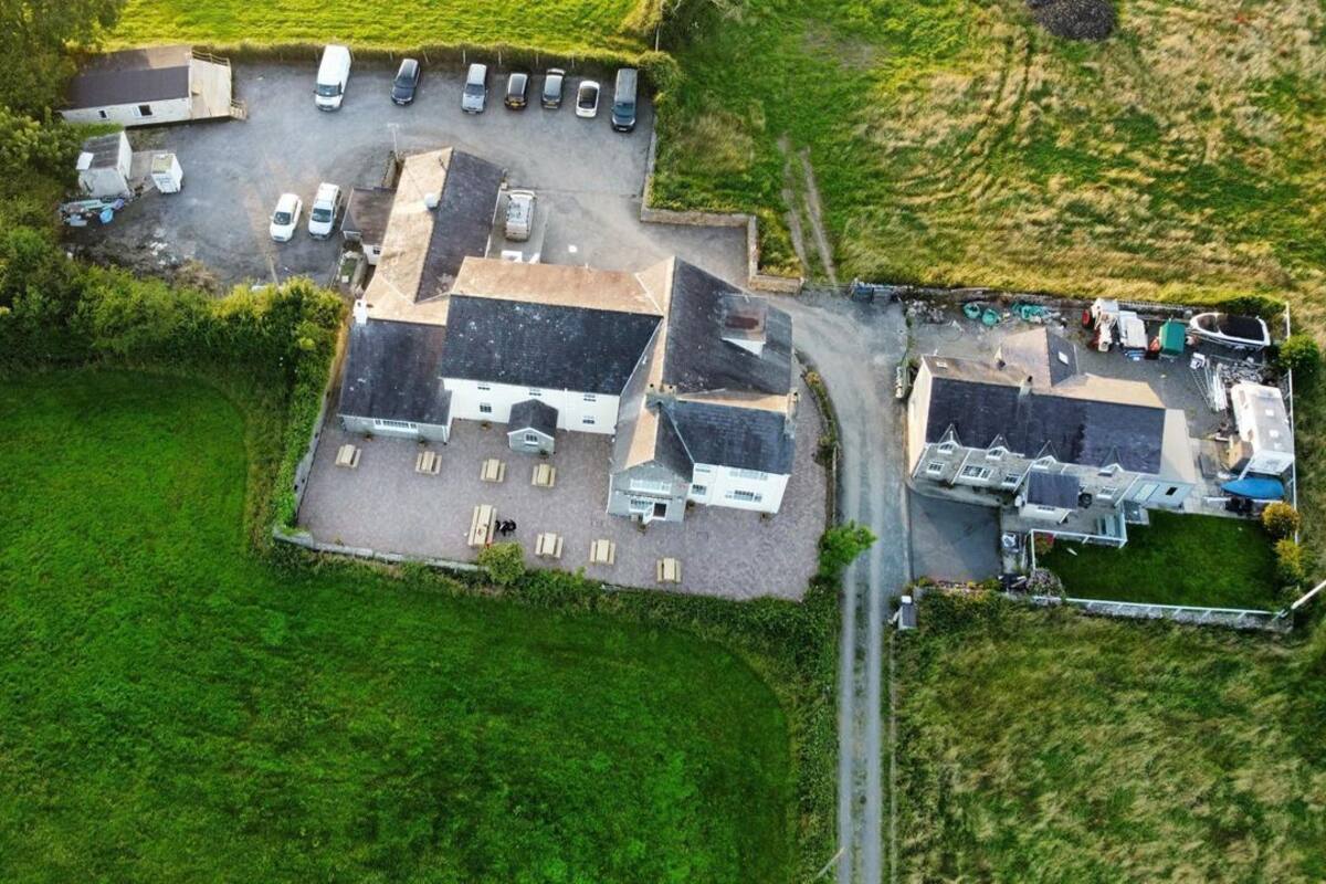 An aerial view of a property with multiple buildings, a parking lot, and a small garden area.