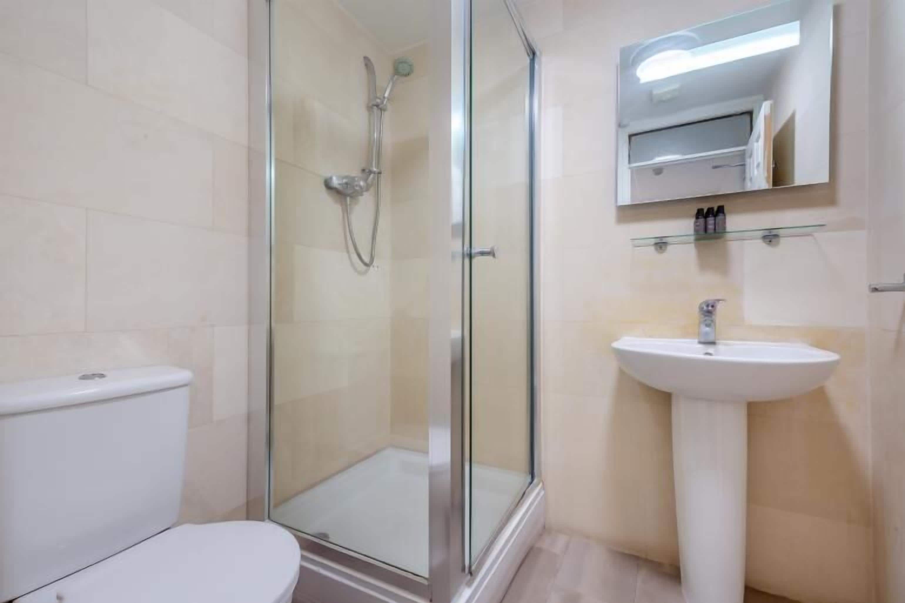 A bathroom with a glass-enclosed shower, a white sink, and a toilet.