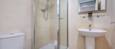 A bathroom with a glass-enclosed shower, a white sink, and a toilet.