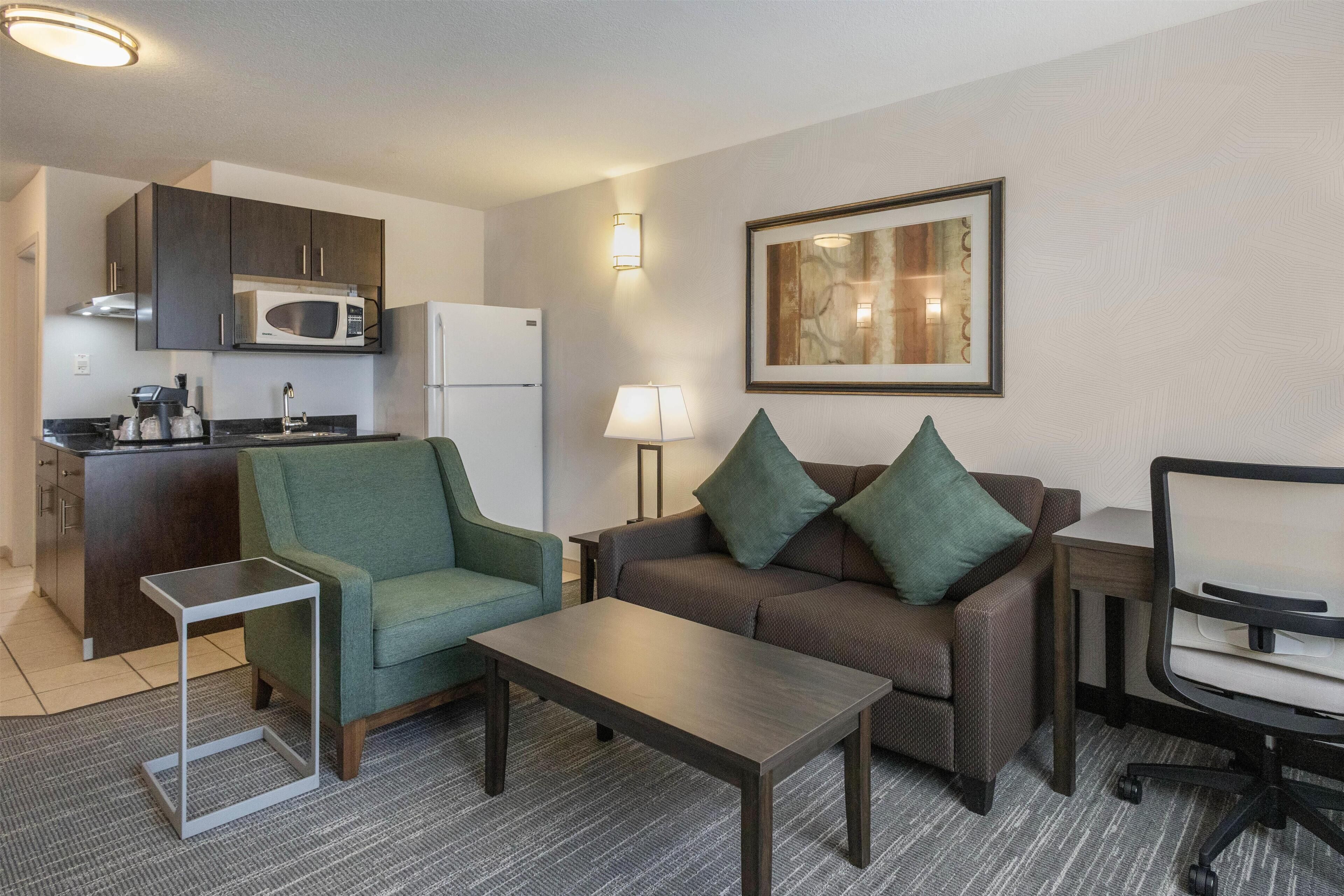 A compact living space with a kitchenette, a sofa, a coffee table, and a lamp.