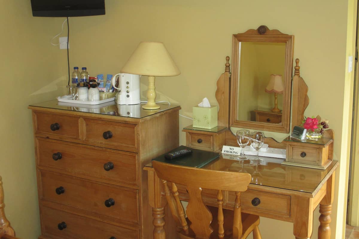 A wooden dresser with a mirror, a lamp, and a "No Smoking" sign.