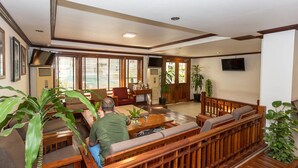 A spacious living area with wooden furniture, large windows, and a television mounted on the wall. - Cheathata CTA Hotel Siem Reap (Siem Reap)