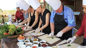 A group of chefs preparing food in a kitchen with various ingredients and utensils on the counter. - Cheathata CTA Hotel Siem Reap (Siem Reap)