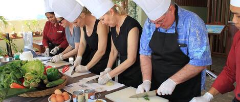 Un grupo de cocineros preparando comida en una cocina con varios ingredientes y utensilios sobre la encimera.