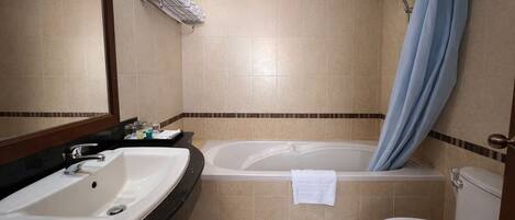 A bathroom with a sink, bathtub, toilet, and a shower curtain.