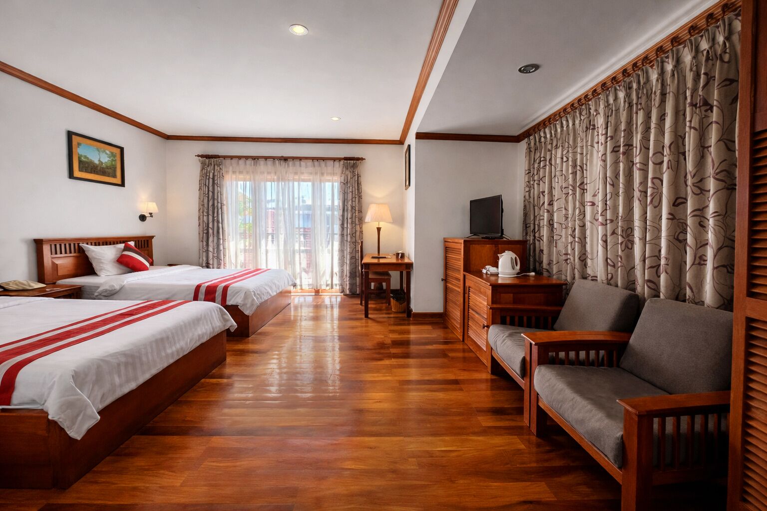 A hotel room with two beds, a sofa, a TV, a lamp, and a view of the outdoors.