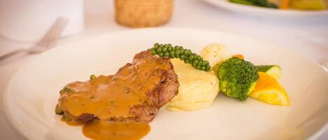 Ein Teller mit einem Steak, Kartoffelpüree, Brokkoli und Orangenscheiben.