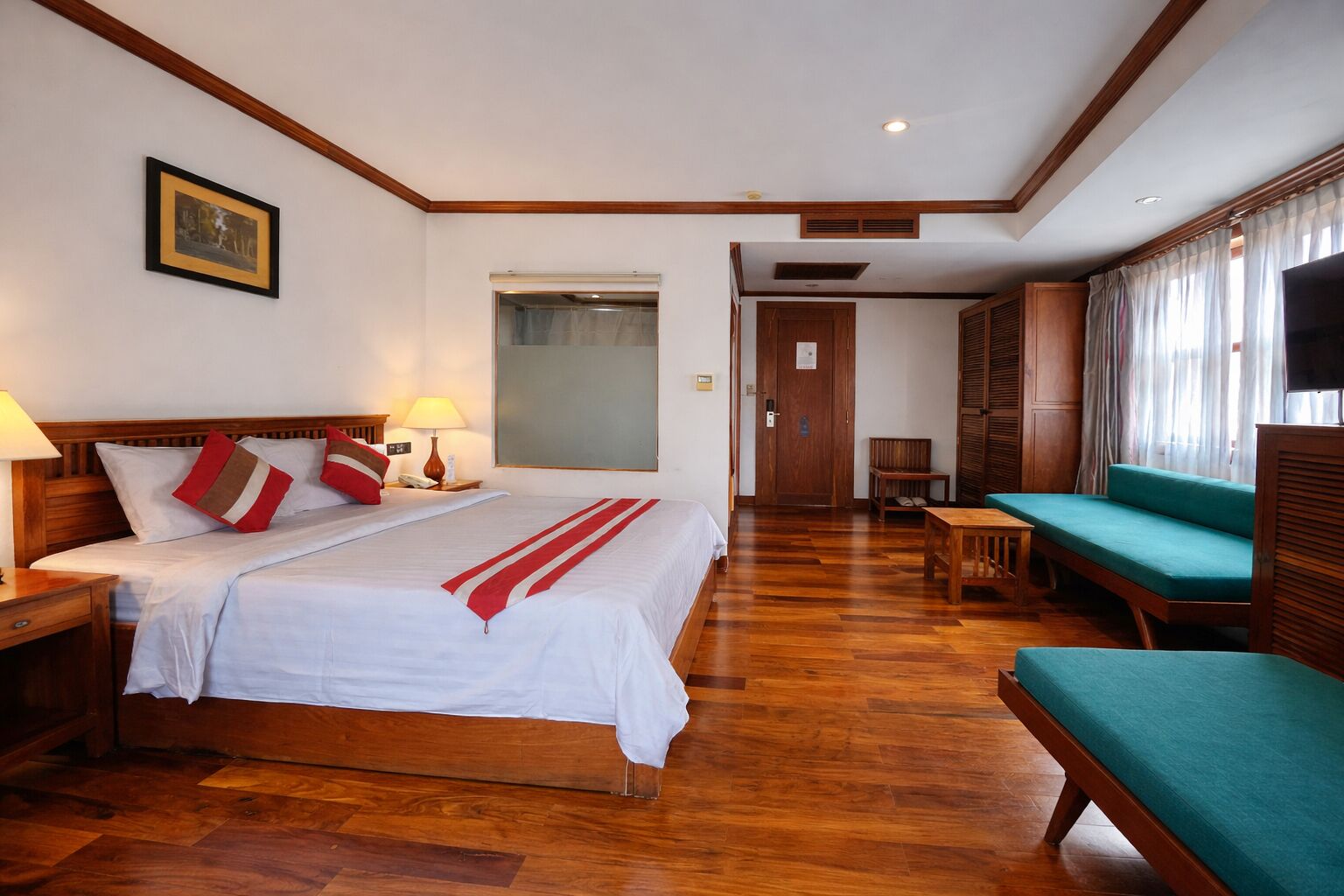 Una habitación de hotel con una cama grande, mesitas de noche, un escritorio, un sofá y un televisor.