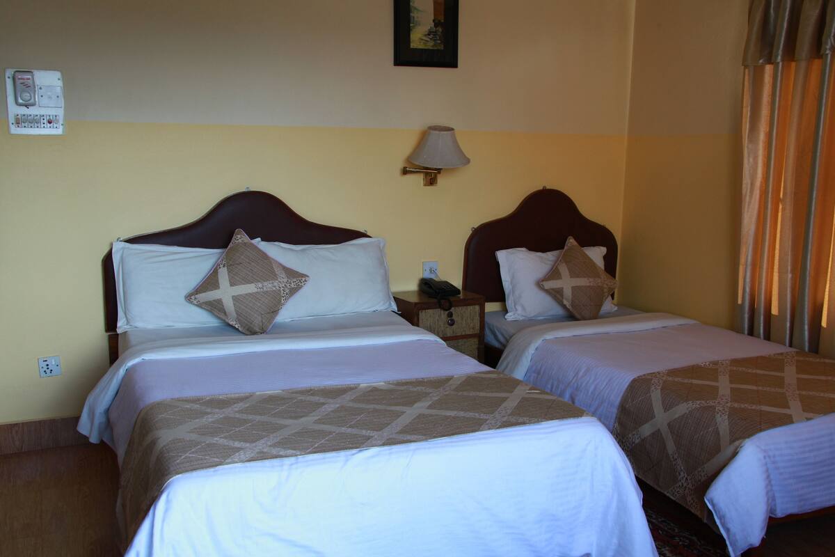 Une chambre d’hôtel avec deux lits, chacun doté d’une tête de lit, d’une table de chevet, d’une lampe et d’un téléphone.