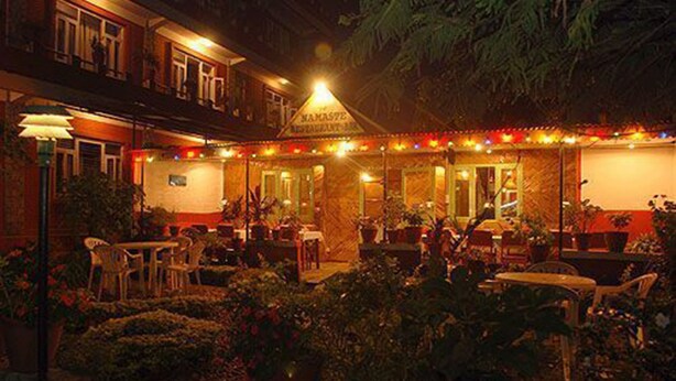 Un restaurante con terraza, un letrero sobre la entrada y un patio bien iluminado.