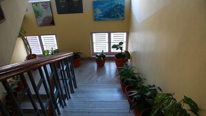 Una escalera con barandas de madera, plantas en macetas y un cuadro en la pared.